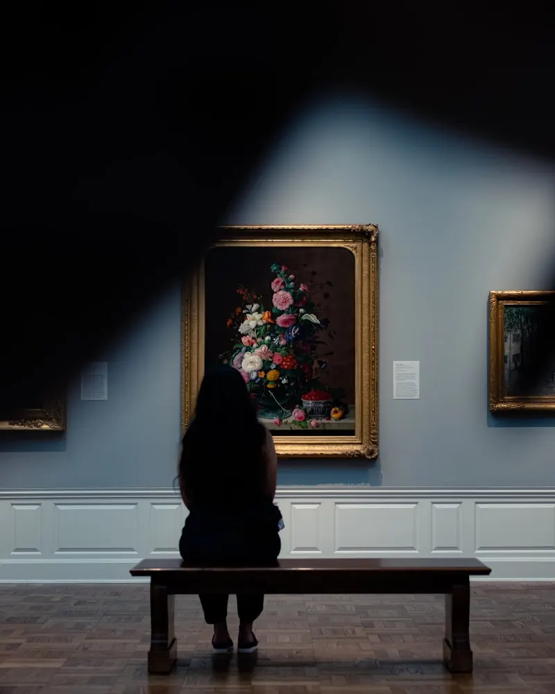 A visitor on a bench before a still life